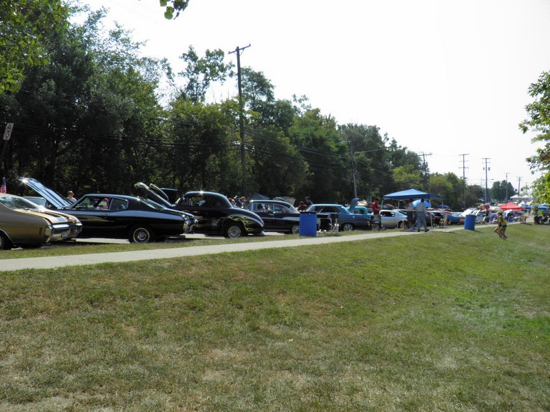 P8290485
The temperature was 90+ degrees.  So everyone had to find the shade where they could, we found the shade of the trees in the park, the perfect place to sit.  Here is a pic of our view of the cars lining the street.